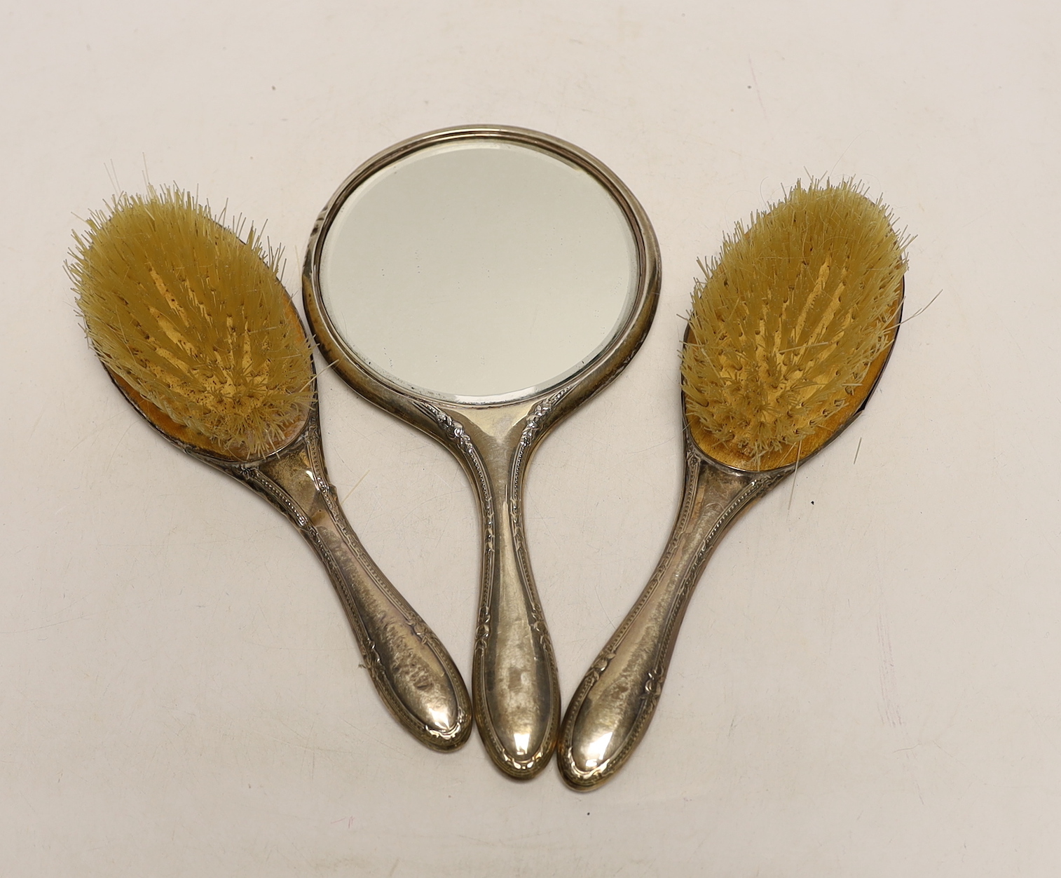 A pair of silver mounted hair brushes and a silver mounted hand mirror.